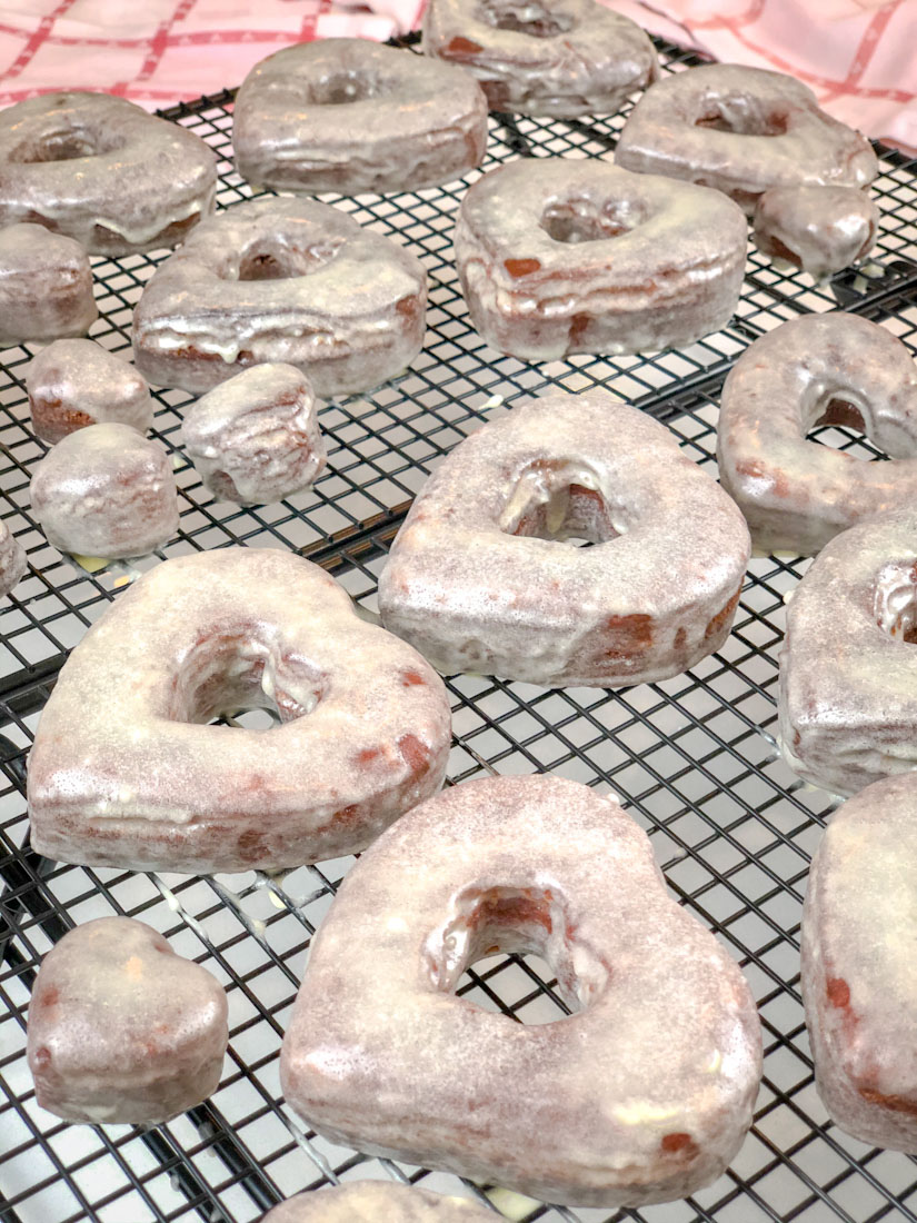 Homemade Red Velvet Glazed Donuts on cooling racks.